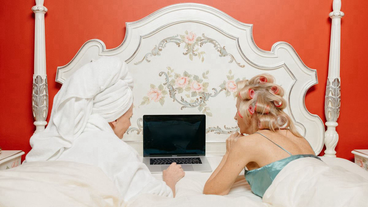 Two friends watching a film together on a laptop screen at home